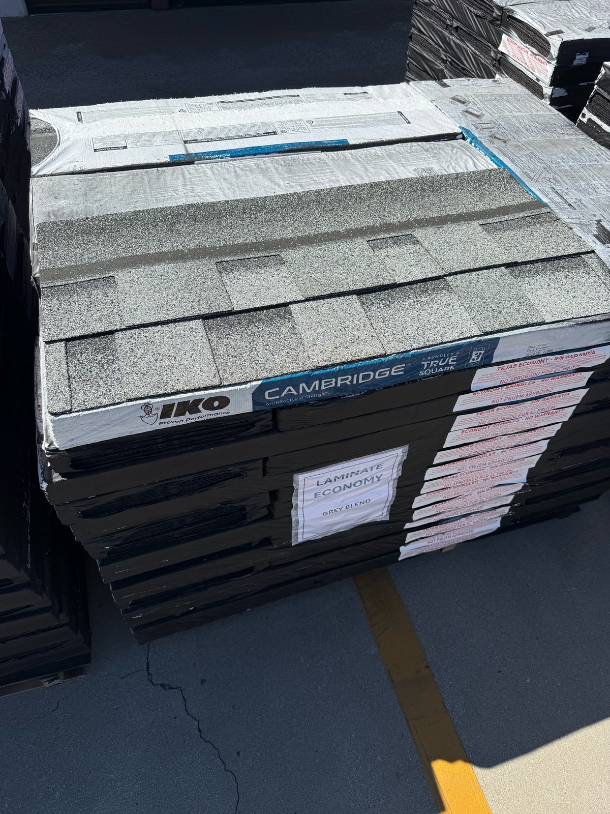 Grey Class 3 economy architectural shingles stacked on pallet at warehouse
